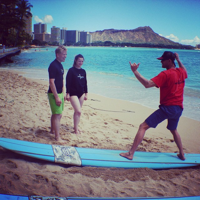 photo - a surf instructor showing how to use the muscles for surfing to new surfers