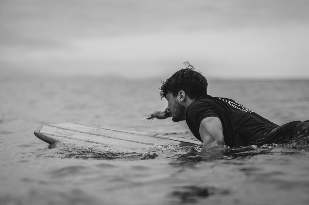 photo - black and white surfer paddling out to surf waves
