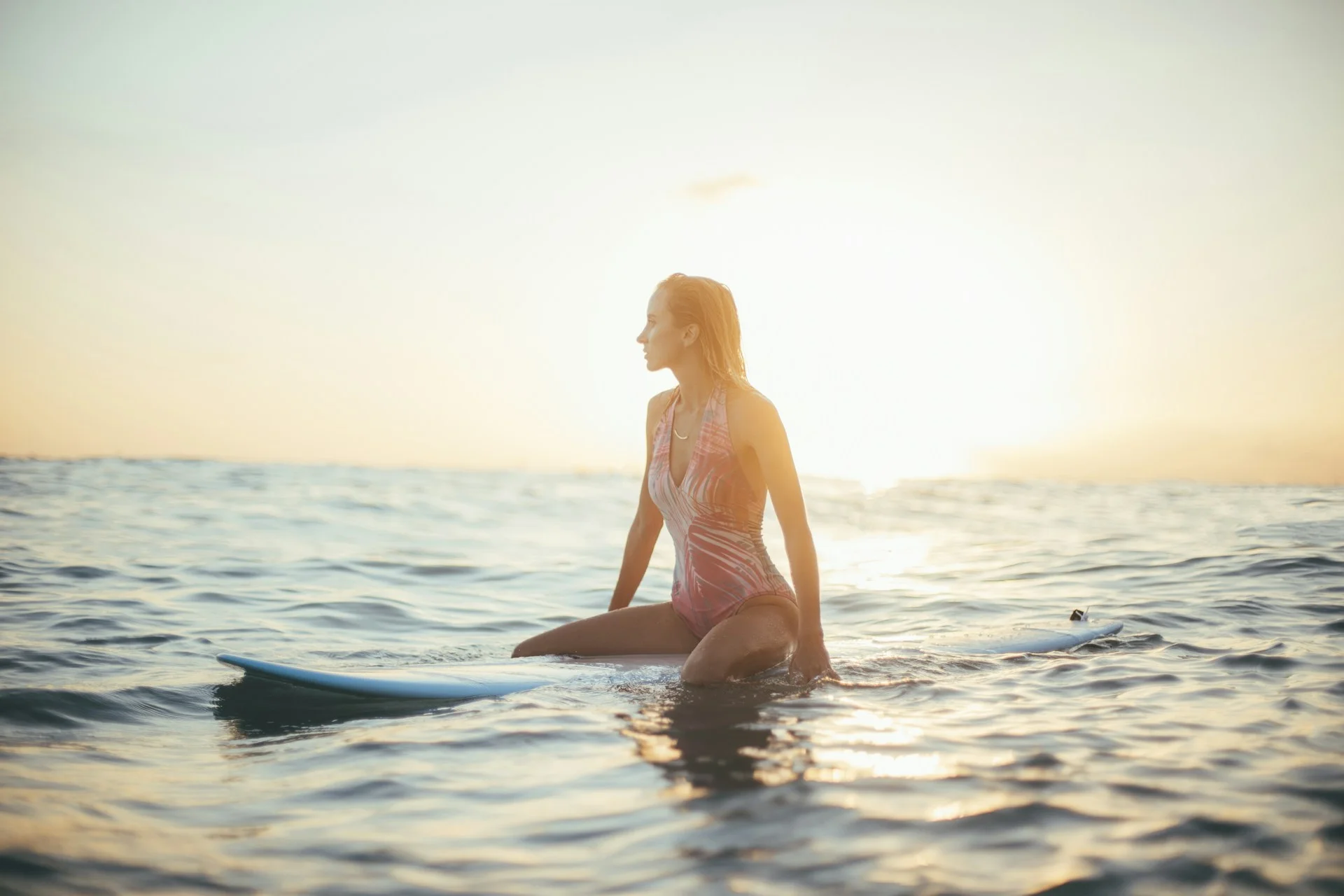 photo - a girl sitting on her surf board in north shore sunset 