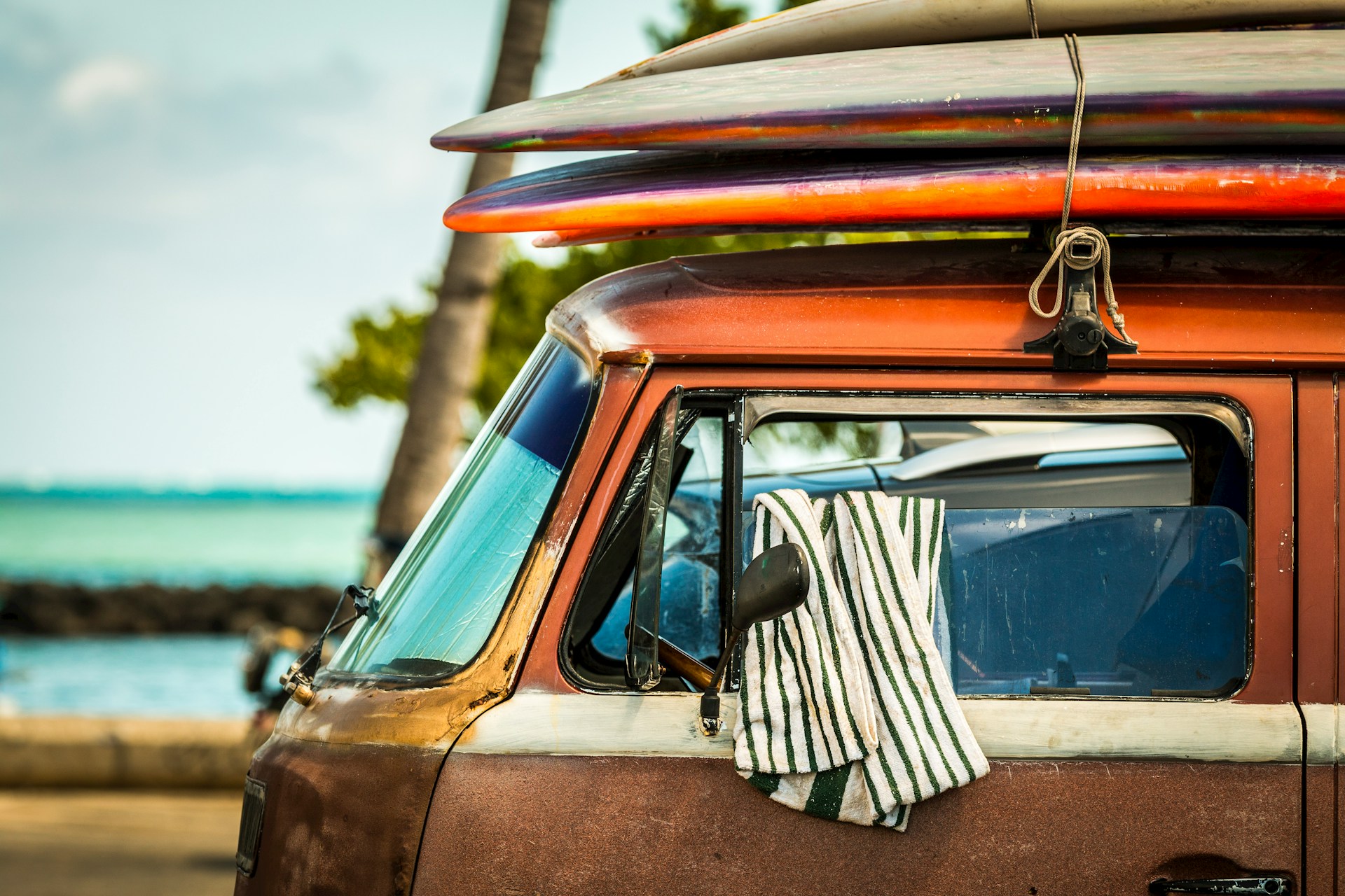 photo - a van parked next to a hawaii beach with surfboards stacked on top, showing value of cost of surfing for those travelling in hawaii