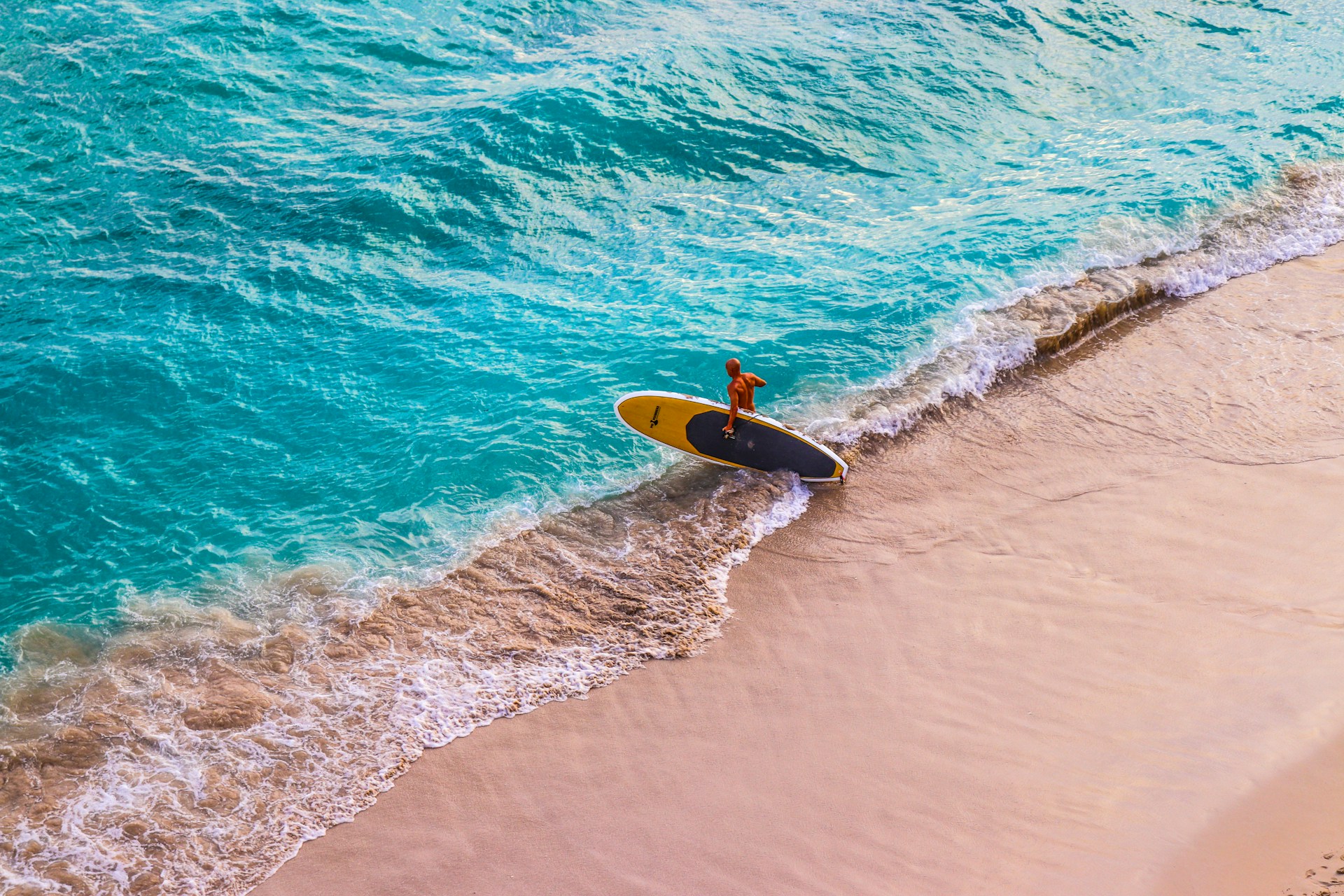 photo - a single surfer going into the ocean to learn how to surf