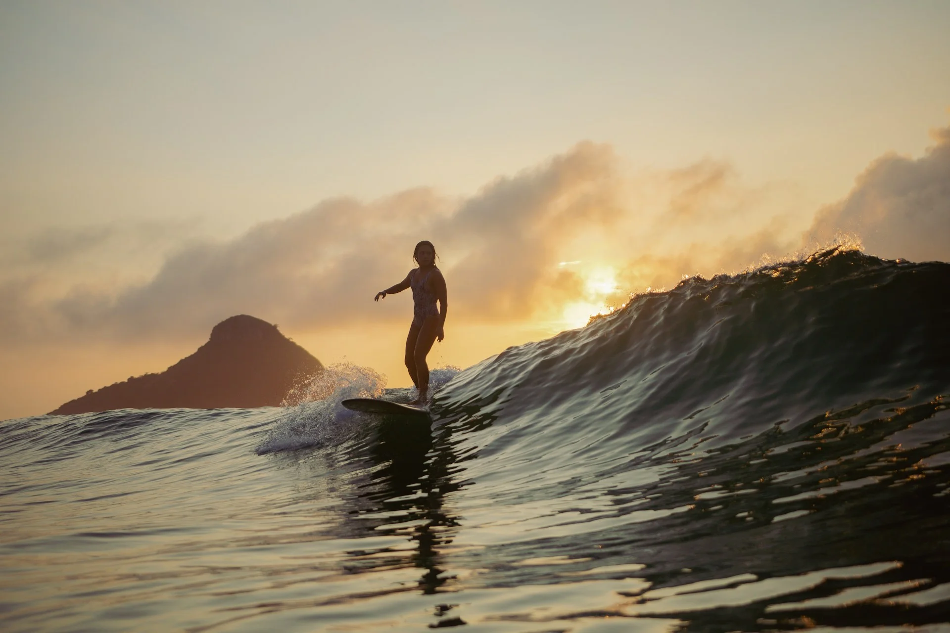 photo - one of female hawaiian surfers catching a wave during sunset