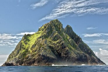 photo - hawaiian mountain in the ocean with people island hopping in Hawaii
