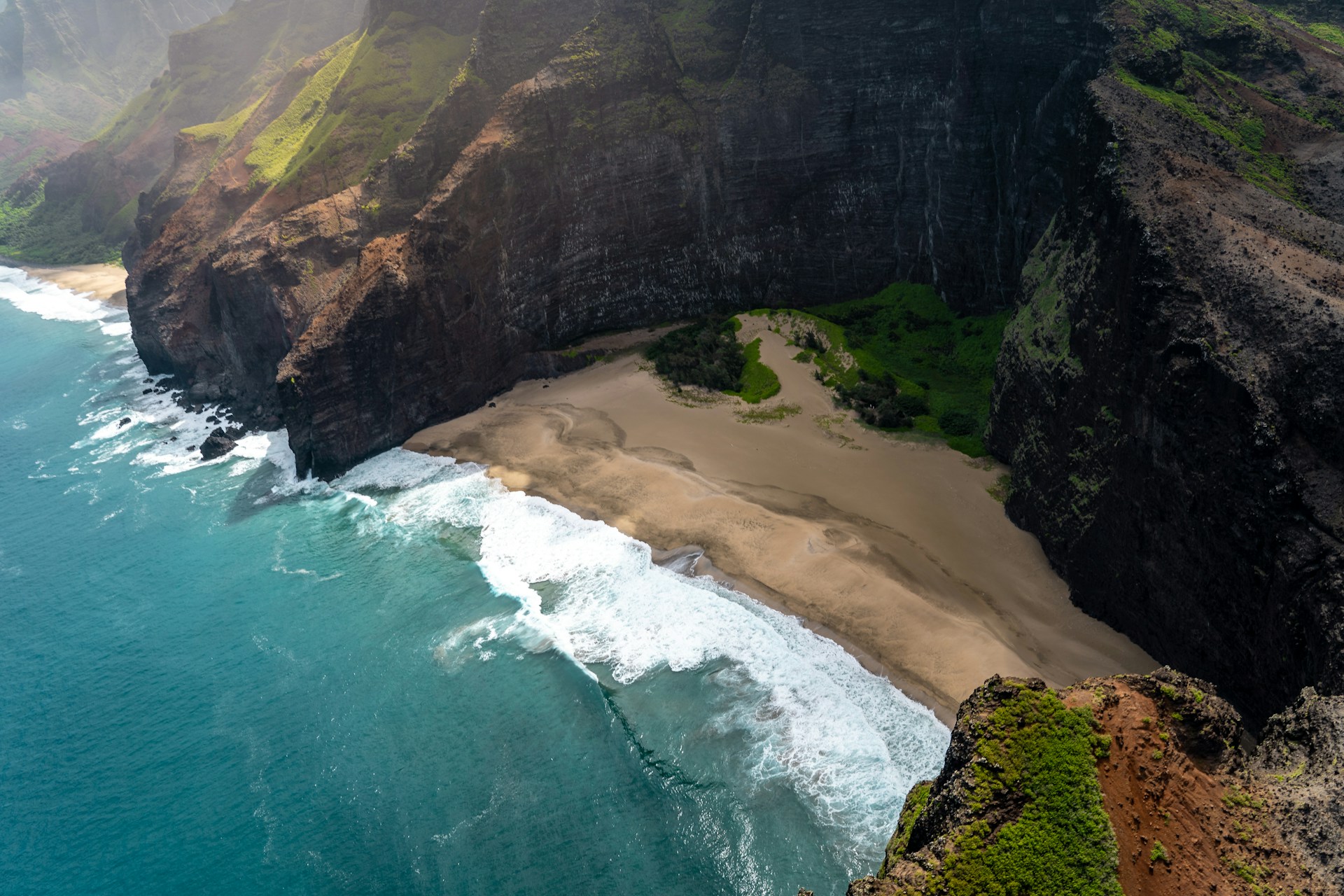 photo - a beautiful birds eye view photo taken from a helicopter of Hawaiian island with a secluded beach and ricky green mountain cliff