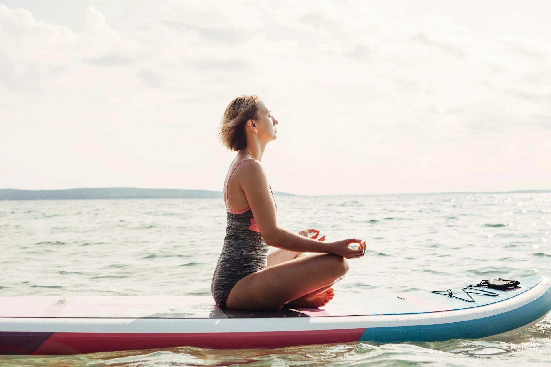 photo - a woman meditating on the water on a surf board benefits of surfing on mental health 