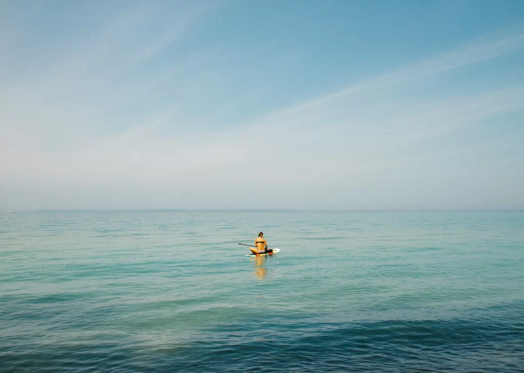 photo - a person on blue water with blue sky above doing paddle boarding oahu