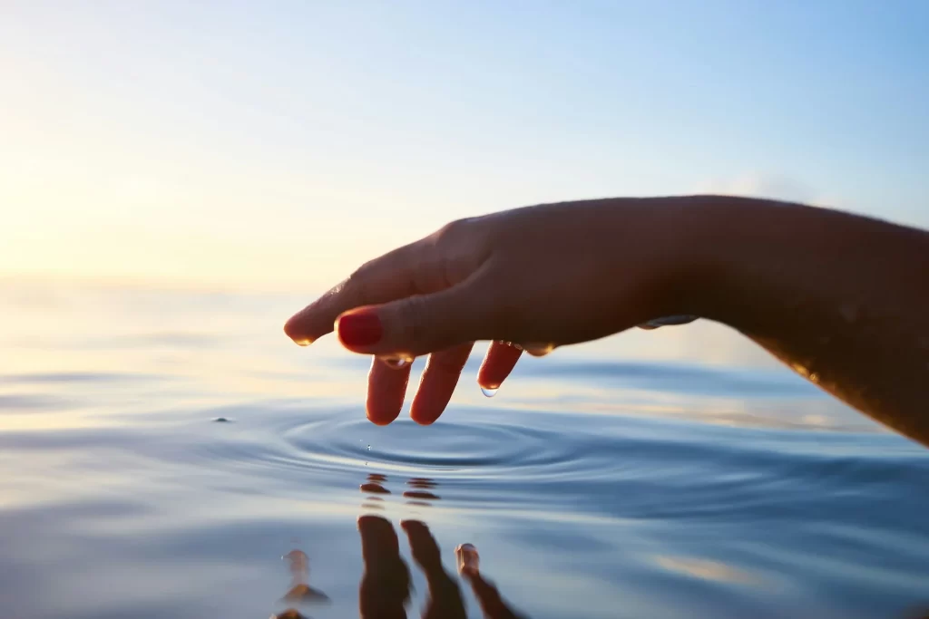 photo - a hand in the ocean trying the water temperature waikiki