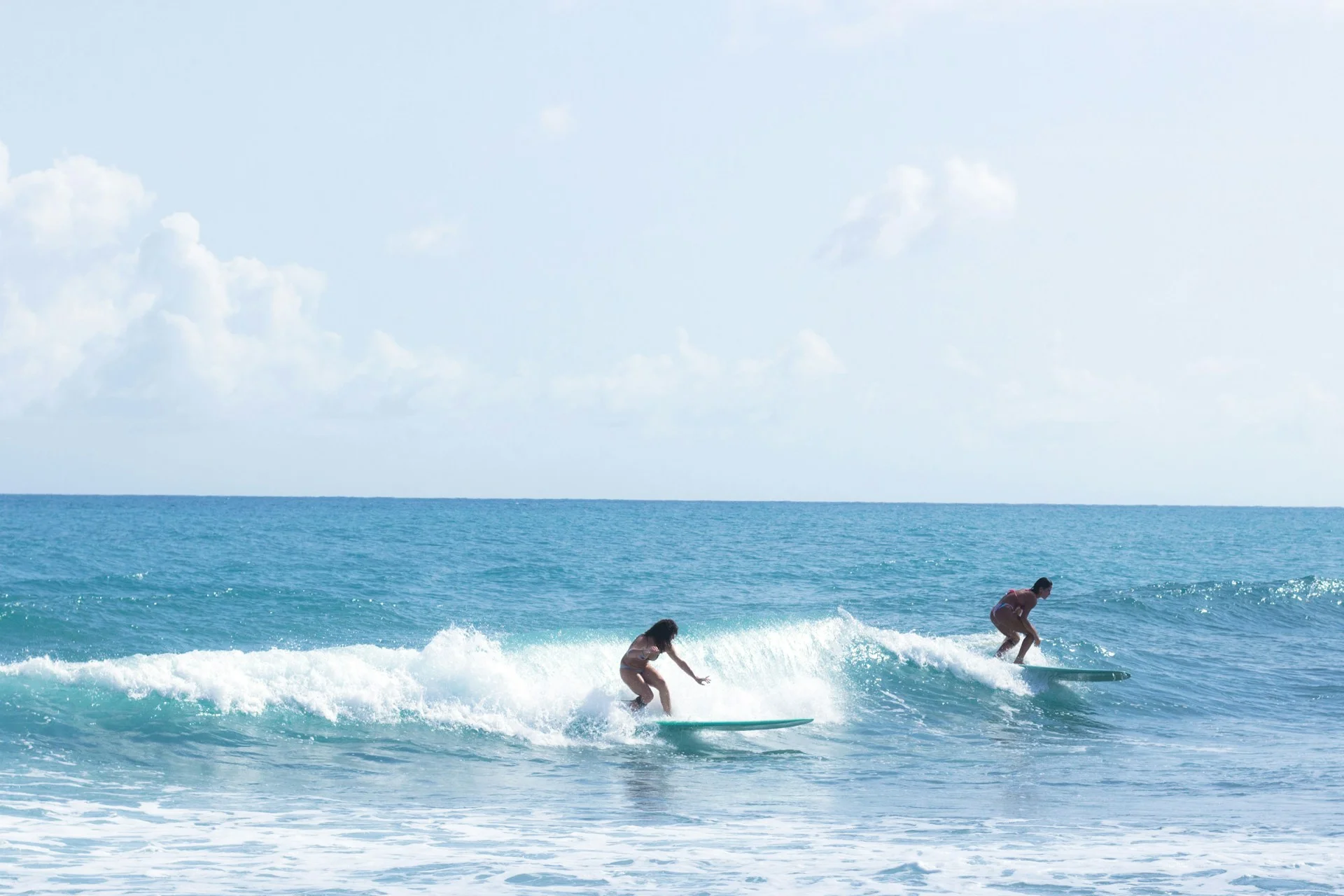 photo - two people are learning how to surf in the ocean