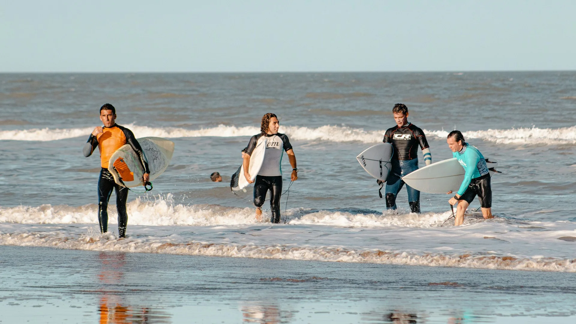 photo - four surfers walking out of the water and discussing: is surfing a sport